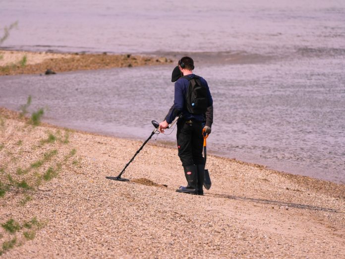 Person er på skattejagt med metal detektor Person er på skattejagt med metal detektor